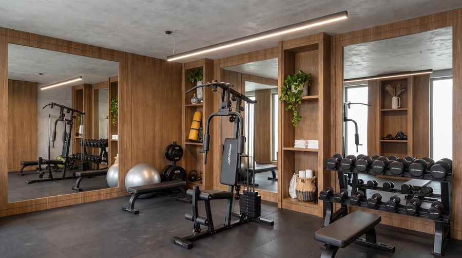 Gimnasio de la planta baja de Ona, con espejos, paneles de madera y zona de pesas